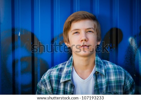 Portrait of young smile teenager in front of blue graffiti