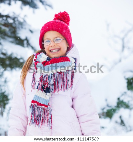 Smiling happy girl having fun outdoors on snowing winter day in Alps playing in snow.