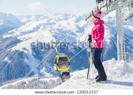 Happy smiling woman in ski goggles against a ski-lift and wonderful winter mountains backgroundagainst wonderful winter mountains background and , Zellertal, Austria