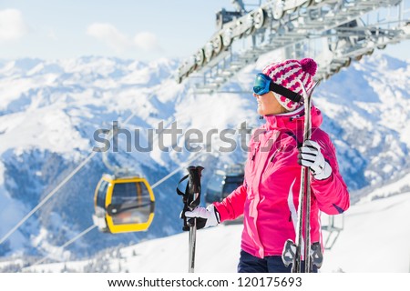 Happy woman in ski goggles against a ski-lift and wonderful winter mountains backgroundagainst wonderful winter mountains background and , Zellertal, Austria