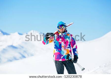Young man with skis and a ski outfit walking in snow at winter outdoor in the Zillertal Arena, Austria