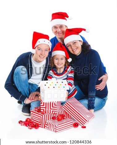 Christmas theme - Portrait of friendly family in Santa\'s hat with gift box and gingerbread house, isolated on white