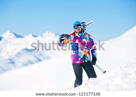 Young man with skis and a ski outfit walking in snow at winter outdoor. Tirol, Austria