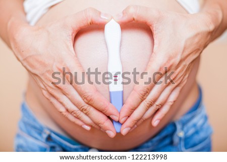 Hand holding positive result pregnancy test