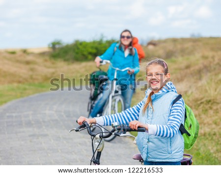 Cute girl with the bike with her mother and grandmother in the park on a spring day