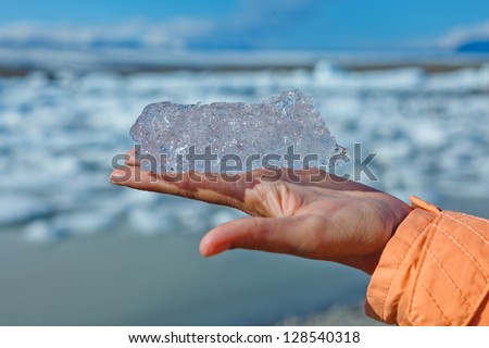 Piece of ice on woman hand. Jokulsarlon a lake in Iceland where icebergs collapsing from Vatnajokull glacier are floating around.