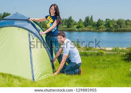 Holiday camping - Man And Woman Couple Setting Up Tent In The Countryside