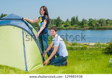 Holiday camping - Man And Woman Couple Setting Up Tent In The Countryside