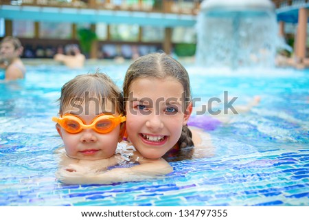 Activities on the pool. Cute kids - sister and brother swimming and playing in water in swimming pool in aquapark