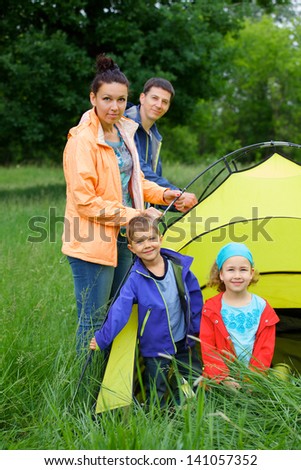 Family with two kids near tent in camping on the nature. Vertical view