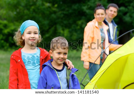 Summer, family camping - lovely sister and brother with parents near camp tent