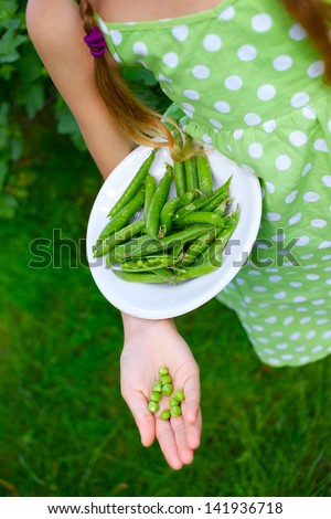 Young girl hand holding organic green natural healthy food produce green Peas in the plate