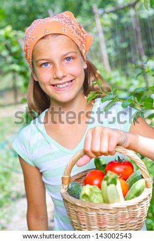 Vegetable garden - portrait of little gardener girl with a basket of organic zucchini and tomatoes