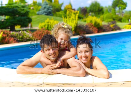 Pretty Little Girl With Her Parent In Swimming Pool Outdoors
