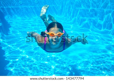 The little girl in the water park swimming underwater and smiling