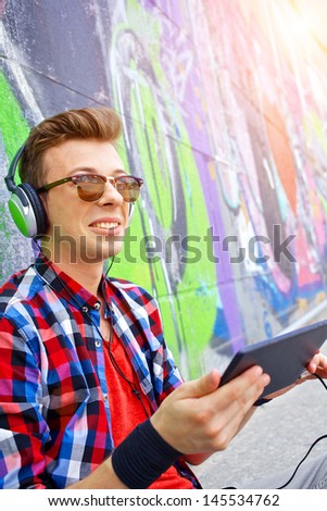 Happy teens boy by painted wall sunrise listening to music.