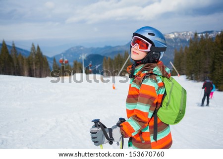 Cute girl on skis in helmet and ski goggles on a sunny day in the mountains