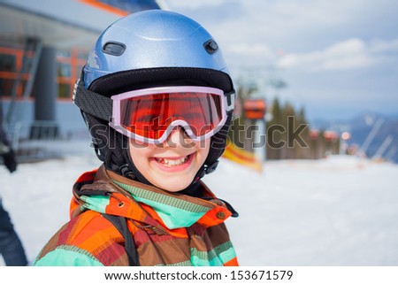 Portrait of girl on skis in helmet and ski goggles on a sunny day in the mountains