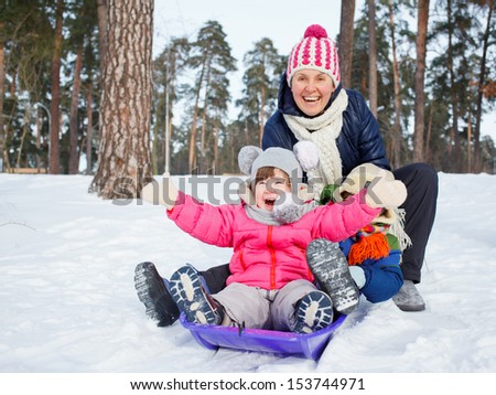 Two kids with mother is sledging in winter-landscape