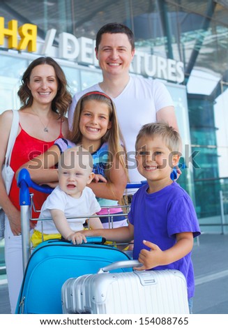 Portrait of traveling family of five with suitcases in airport