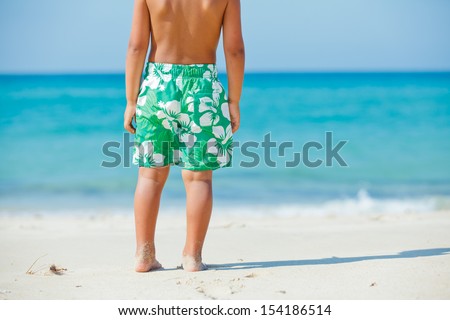 Walking on the beach. Close up on boy legs walking along the sea side.