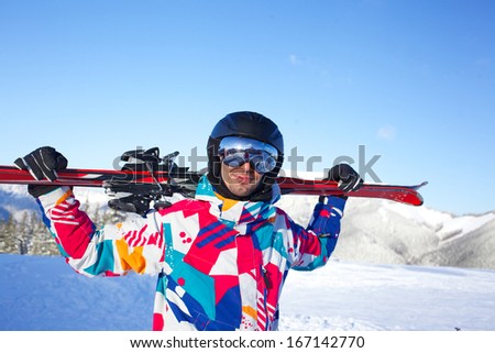 Young man ski goggles and a helmet holding ski in the mountains