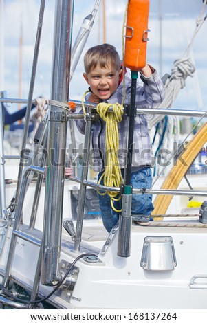 Cute happy boy rests on Yacht Club and is glad at life.