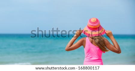 Back view of beautiful girl in pink hat and on background sea