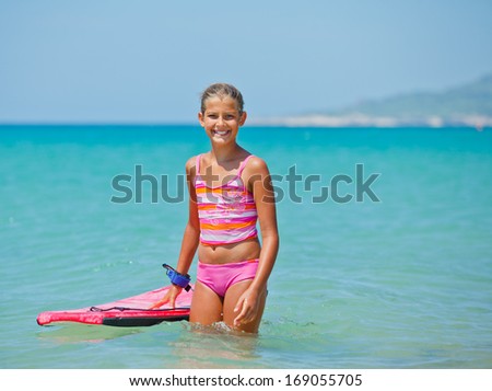 Cute surfer. Girl with surfboard standing in ocean.