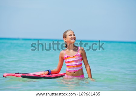 Cute surfer. Girl with surfboard standing in ocean.