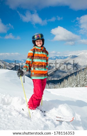 Cute girl on skis in helmet and ski goggles on a sunny day in the mountains