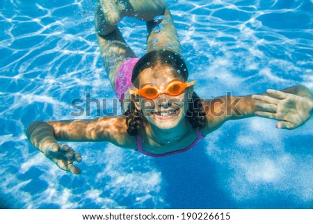 The cute girl swimming underwater and smiling