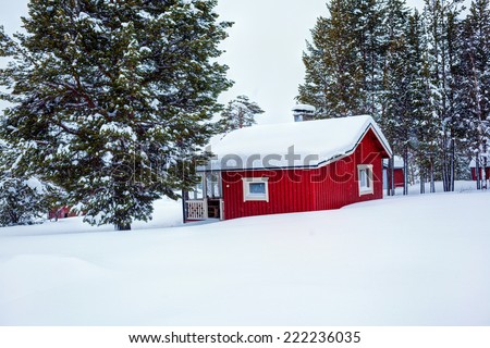 Red wooden Finnish house in winter forest covered with snow