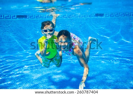 Underwater happy cute girl and boy in swimming pool