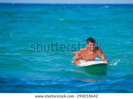 Strong young man learning to surf. Summer vacation