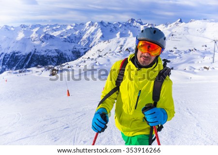 Handsome active man with sky in helmet and goggles. Standing on sloap in Alps mountains