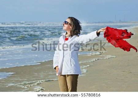 Breeze. Beautiful sweet woman playing with the wind and a red scarf on the sandy ocean