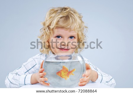 Cute little boy with a fish in an aquarium. In the studio