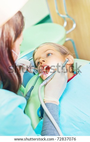 At the dentist. Photo of small girl with open mouth while it being examined by dentist.