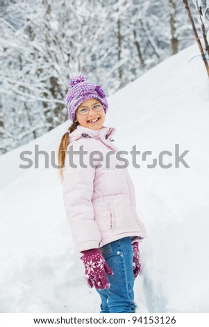 Smiling happy girl having fun outdoors on snowing winter day in Alps playing in snow. Vertical view