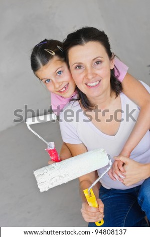Portrait happy mother and douther with roller for painting a wall