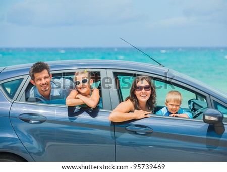 A family of four, mother, father, son and daughter driving in a car on a sunny day in hot location, backround sea