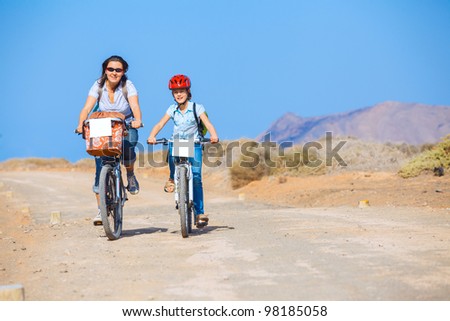 Girl with her mother having a weekend excursion on their bikes on a summer day in beautiful landscape