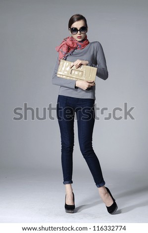 full-length fashion girl with handbag posing over gray background
