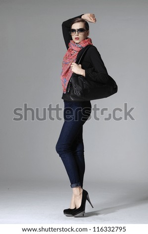 Full body fashion model wearing sunglasses in scarf on gray background