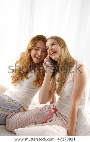 Young two woman talking on cell phone sitting on bed