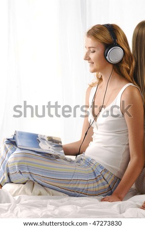 Beautiful girl reading book and listening music isolated on bed