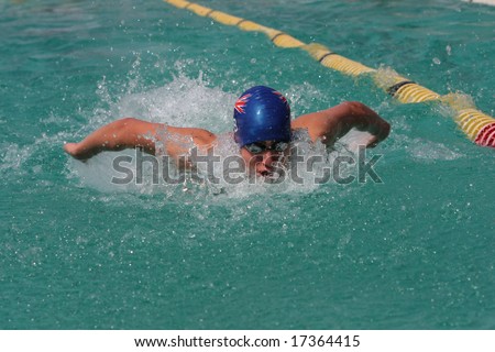 Swimmer doing butterfly stroke with face out of water and arms behind back