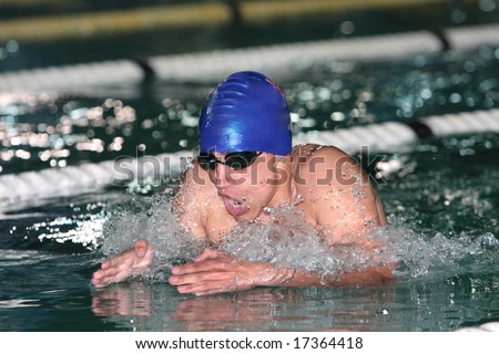 Action photo of breaststroke swimmer with blue cap with hands above water