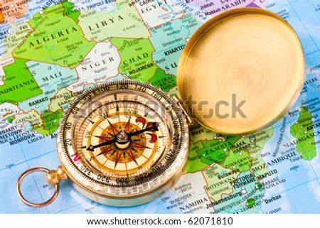 A brass compass sat on a map of africa